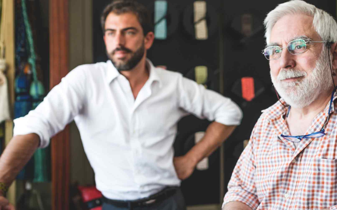 Elderly business owner with a younger man in a workshop, symbolizing the transfer of knowledge and leadership